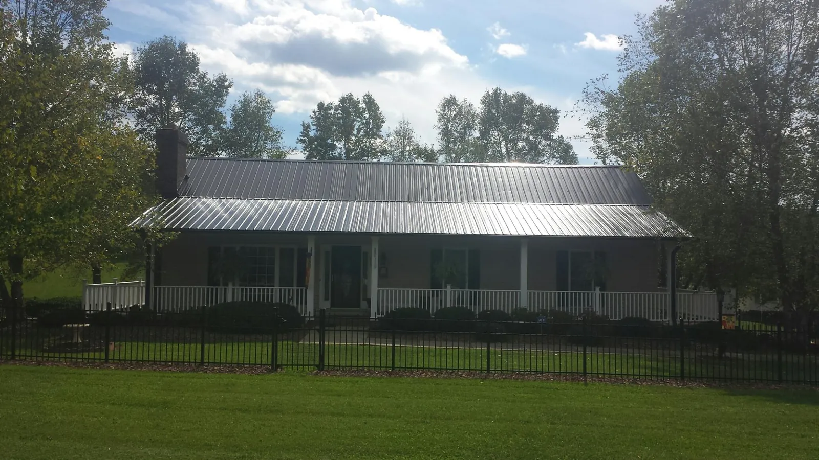 Gray metal roof on a brick ranch with a full width front porch — Gutter Guard Installation work by our crew in Corydon