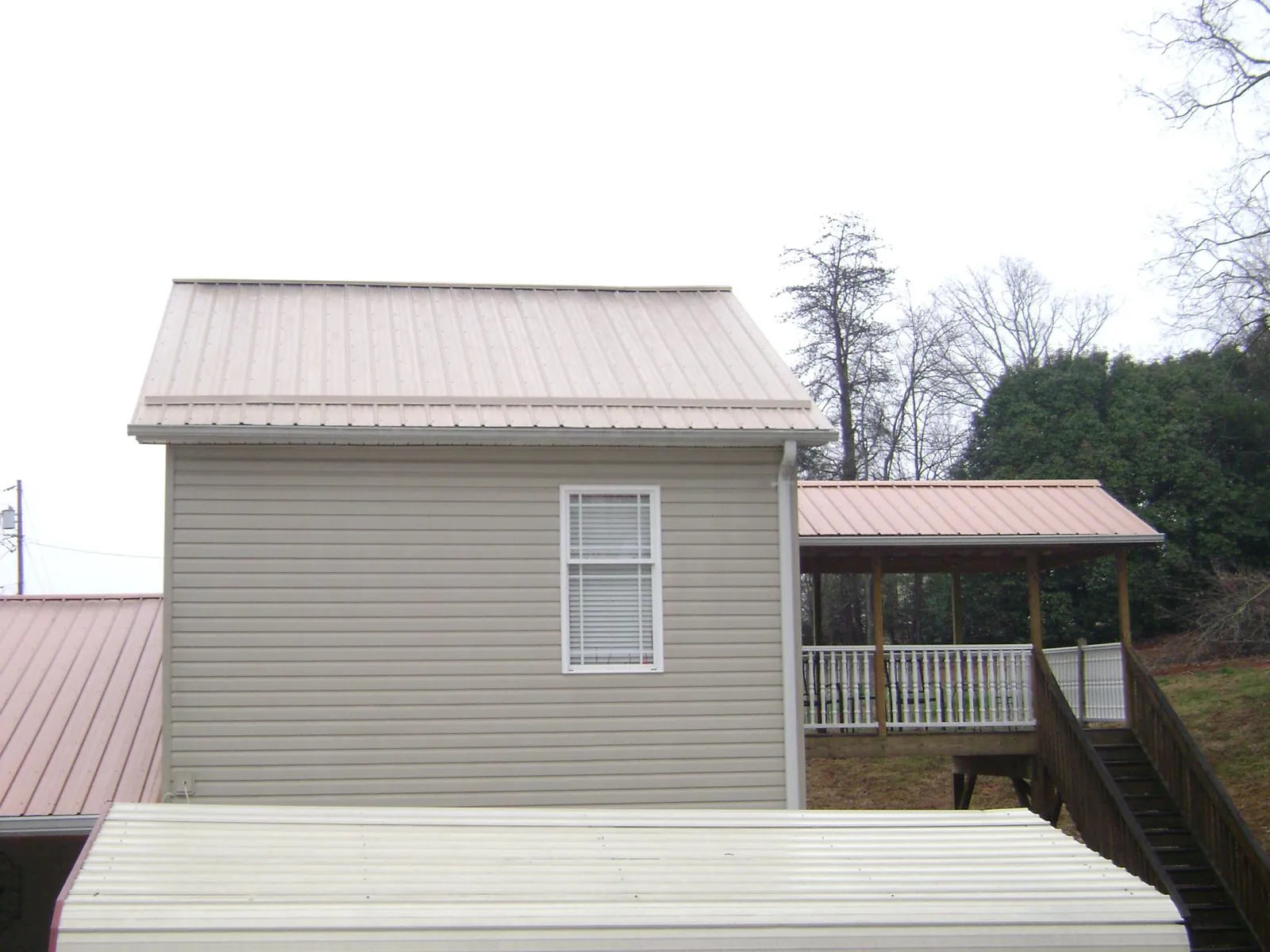 Tan metal roofs on a two story addition and attached porch, from a Roof Replacement job in Corydon